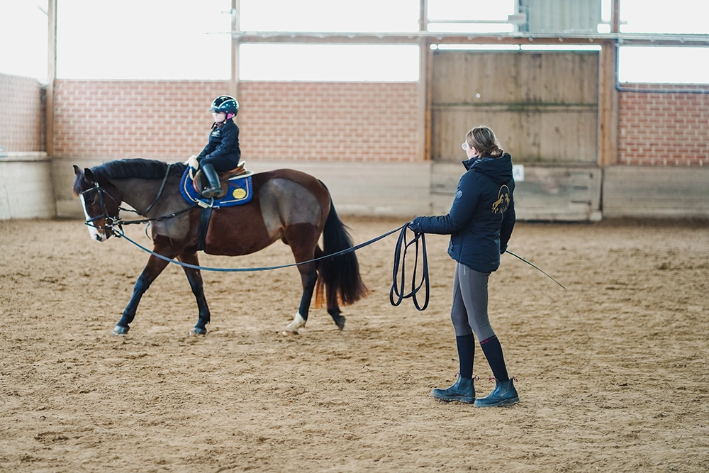 Reitschülerin auf  Pferd bein Longenunterricht, Reitlehrerin vom Reitstall Pavel hält die Longe.